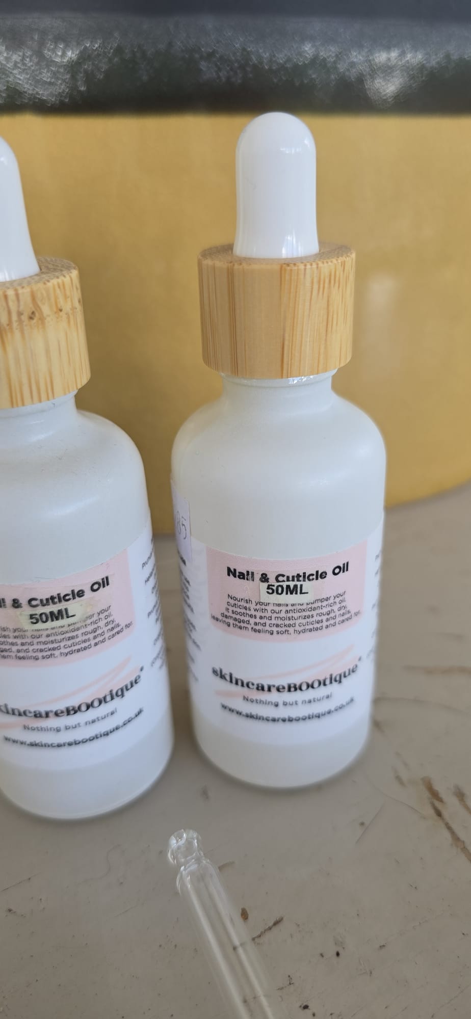 Two bottles of skincareBOOtique nail and cuticle oil with droppers on a surface.