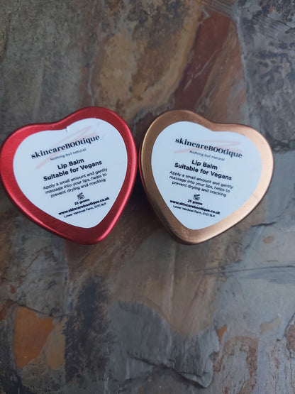 Two heart-shaped lip balm containers from skincareBOOtique on a textured surface.